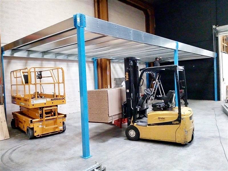 Structure de mezzanine en cours de montage, poteaux bleus et poutres galvanisées, à Oullins
